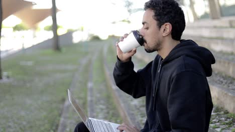 Hombre-Usando-Una-Computadora-Portátil-Y-Tomando-Café-Para-Llevar